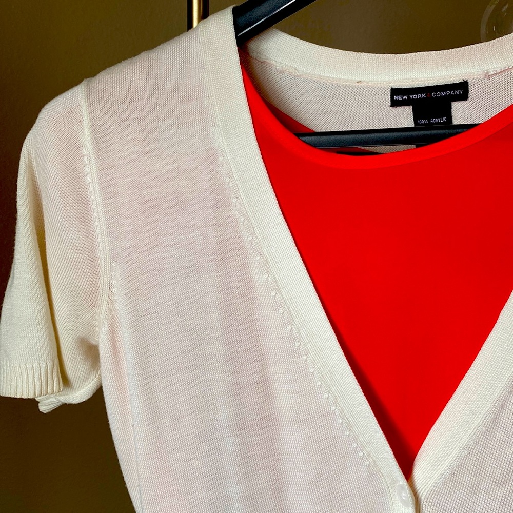 Cream cardigan with short sleeves, ribbed cuffs/hem, & delicate neckline detail